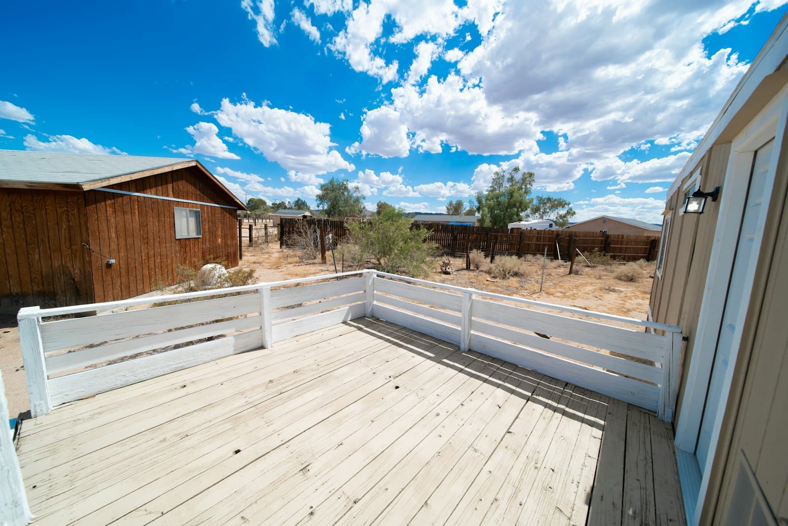 A clean light-toned deck with a white perimeter fence next to a residential home — the premium look most Canadians are paying for when they choose PVC over composite.