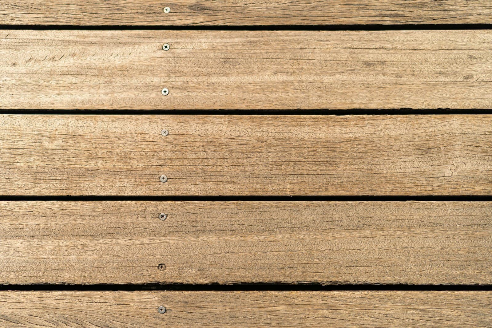 Close-up of a weathered composite deck surface with fastener heads showing — the kind of board face where mold and mildew take hold in Ontario's humid summer months.